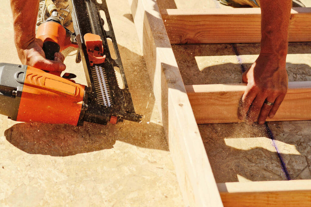 Worker building wall with lumber before tilting it in place.